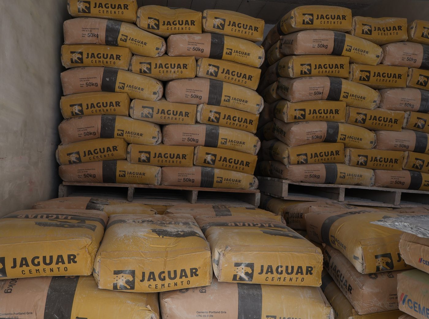Sacos de cemento Jaguar de 50 kg apilados en almacén